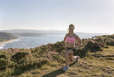 Spain, Asturias, sportswoman on the coast, smiling - MGOF002189