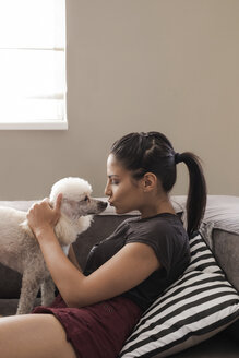 Young woman at home caressing her dog - MOMF000021