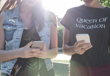 Two female friends with smartphones, partial view - MOMF000031