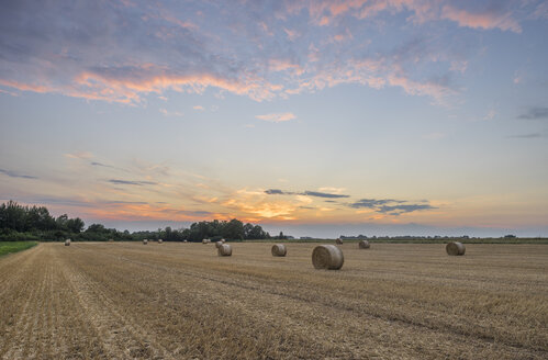 Deutschland, Niedersachsen, Strohballen auf einem Feld bei Sonnenuntergang - PVCF000883