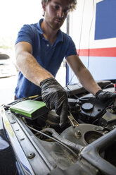 Mechaniker setzt eine Batterieklemme in ein Auto ein - ABZF000940
