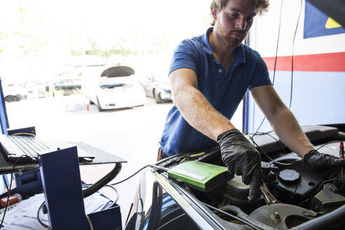 Mechaniker setzt eine Batterieklemme in ein Auto ein - ABZF000941