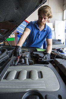 Ein Mechaniker kontrolliert das Öl eines Autos - ABZF000942