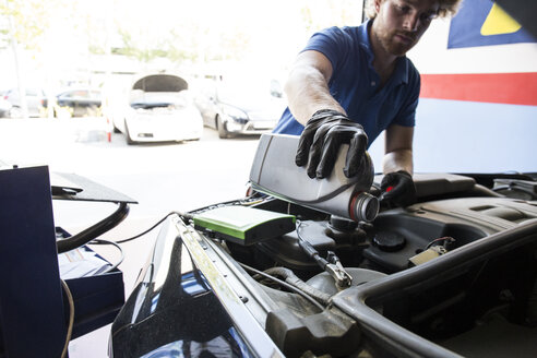 Mechaniker füllt Öl in ein Auto nach - ABZF000948