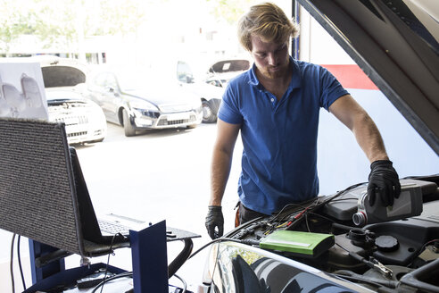 Mechaniker füllt Öl in ein Auto nach - ABZF000950