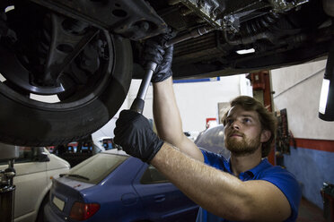 Mechanic fixing suspended car in his workshop - ABZF000952