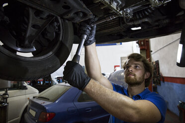 Mechaniker, der in seiner Werkstatt ein aufgehängter Wagen repariert - ABZF000952