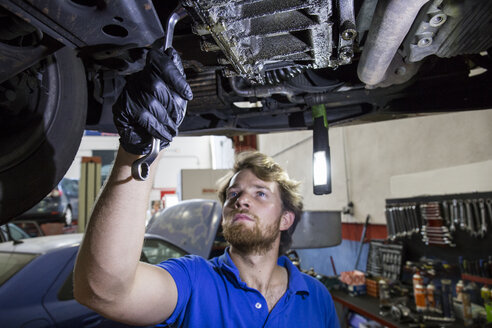 Mechaniker, der in seiner Werkstatt ein aufgehängter Wagen repariert - ABZF000954