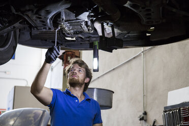 Mechaniker, der in seiner Werkstatt ein aufgehängter Wagen repariert - ABZF000955