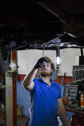 Mechanic fixing suspended car in his workshop - ABZF000956