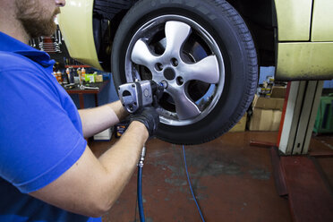 Mechanic fixing a car wheel in a workshop - ABZF000959