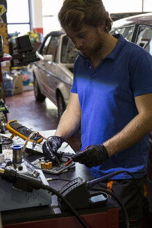 Mechaniker repariert ein elektronisches Auto in seiner Werkstatt - ABZF000964