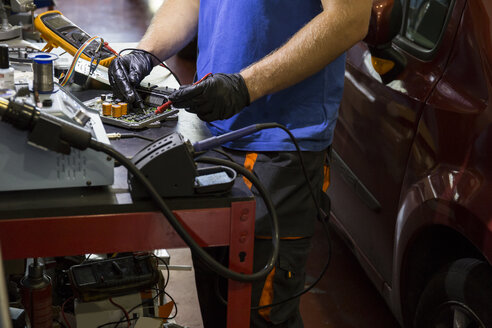 Mechaniker repariert ein elektronisches Auto in seiner Werkstatt - ABZF000965