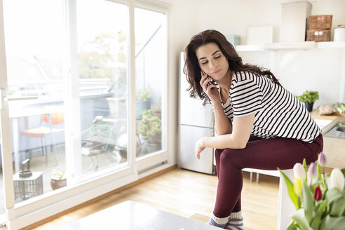 Junge Frau am Handy in der Küche - PESF000269