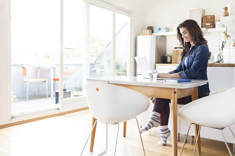 Lächelnde junge Frau zu Hause am Laptop, lizenzfreies Stockfoto