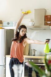 Junge Frau in der Küche, die putzt und Musik hört - PESF000280