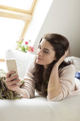 Relaxed woman lying on couch using cell phone - PESF000339