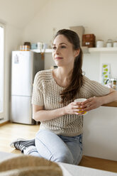 Young woman with cup of coffee relaxing in kitchen - PESF000350