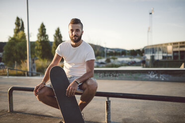 Porträt eines Skateboarders, der in einem Skatepark sitzt - RAEF001388