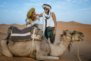 Berber man with woman tourist with a camel in the desert - KIJF000704