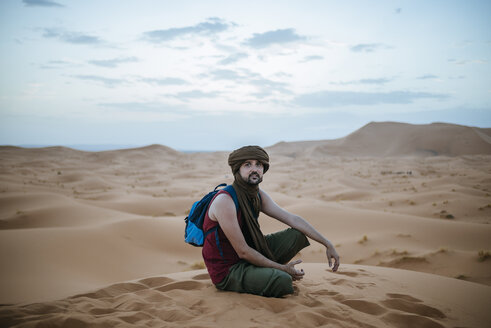 Tourist wearing turban sitting in the desert - KIJF000713