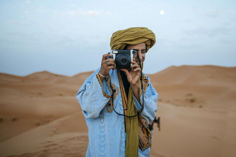 Junger Berber beim Fotografieren mit Kamera, lizenzfreies Stockfoto