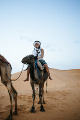 Woman with turban riding a camel in the desert - KIJF000717