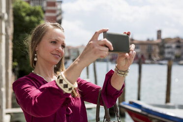 Italy, Venice, tourist taking pictures with smartphone - MAUF000721