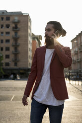 Young man with full beard telephoning with smartphone at backlight - MAUF000732