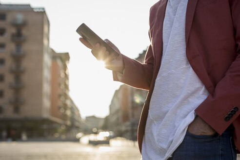 Young man with smartphone at backlight, partial view - MAUF000734