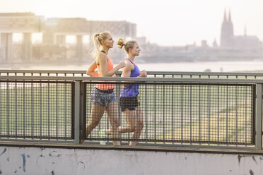 Zwei junge Frauen laufen auf einer Brücke - MADF001085