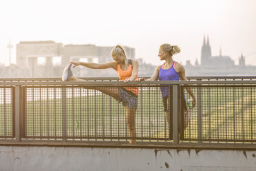 Two young women stretching on bridge - MADF001087