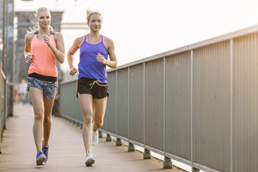 Zwei junge Frauen laufen auf einer Brücke - MADF001088