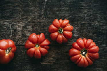 Vier selbstgezogene Bio-Ochsenherz-Tomaten auf dunklem Holz - IPF000325