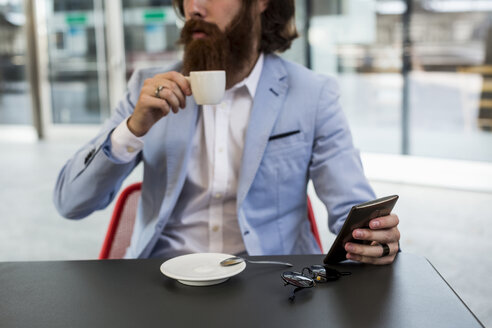 Stilvoller Geschäftsmann hält Handy in einem Café - MAUF000749