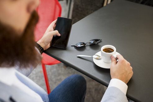 Stilvoller Geschäftsmann hält Handy in einem Café - MAUF000751