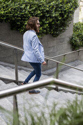 Stylish businessman walking on stairs outdoors - MAUF000772