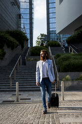 Stylish businessman walking with suitcase outdoors - MAUF000777