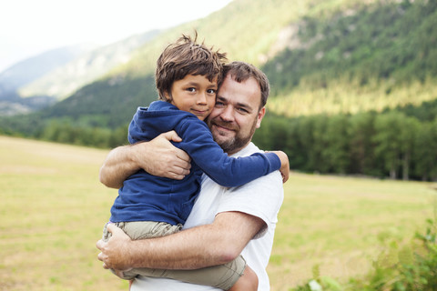 Porträt von Vater und kleinem Sohn, die sich umarmen, lizenzfreies Stockfoto