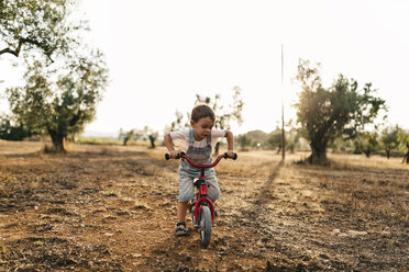 Kleiner Junge mit Kinderfahrrad auf einem Feld - JRFF000818