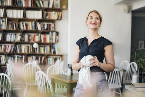 Lächelnde Frau trocknet Tasse in einem Cafe - KNSF000196