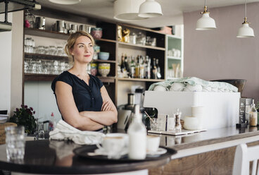 Selbstbewusste Frau hinter dem Tresen eines Cafés - KNSF000197