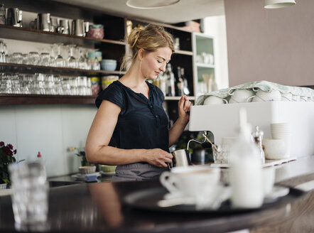 Frau in einem Café bereitet Milchschaum für Kaffee zu - KNSF000198