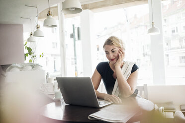 Woman using laptop in a cafe - KNSF000201