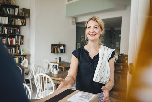 Lächelnde Frau empfängt Paket in einem Café - KNSF000202