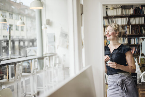 Lächelnde Frau in einem Cafe, die aus dem Fenster schaut - KNSF000212