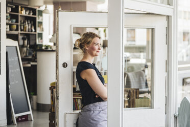 Lächelnde Frau in einem Cafe, die aus dem Fenster schaut - KNSF000223