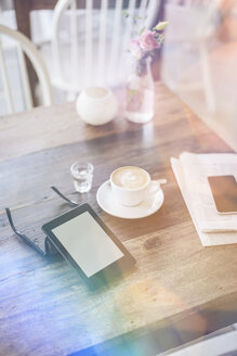 E-Book, Sonnenbrille und eine Tasse Kaffee auf dem Tisch in einem Cafe - KNSF000232