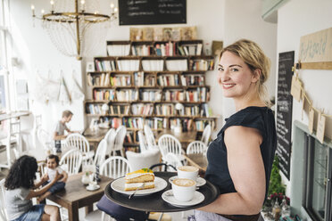 Lächelnde Kellnerin in einem Café, die Kuchen und Kaffee serviert - KNSF000237