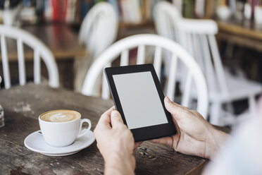Mann hält E-Book in einem Cafe - KNSF000239